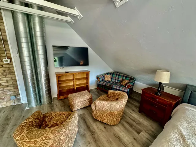Attic living space featuring wood-finish flooring, exposed brick wall, and visible ductwork