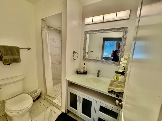 Bathroom featuring a single vanity with a white countertop, framed mirror, and integrated lighting