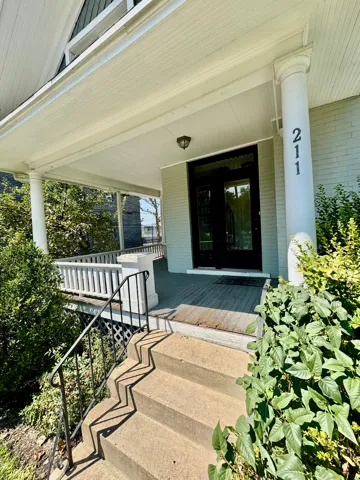 Front entry featuring concrete steps with a black wrought iron railing, leading to a covered porch