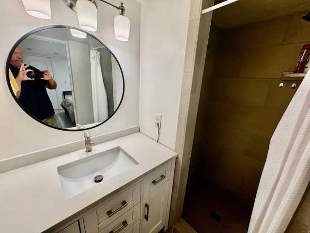 Contemporary bathroom featuring a light-toned vanity with a rectangular undermount sink, brushed nickel faucet, and a large circular mirror