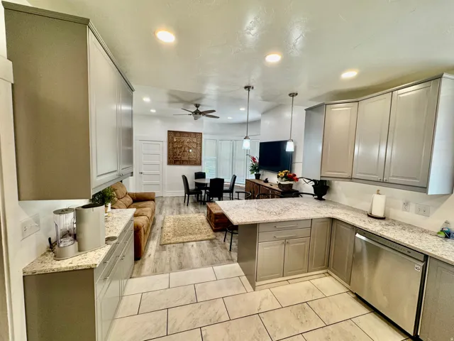 Kitchen featuring light gray cabinetry, light-toned countertops, and a stainless steel dishwasher