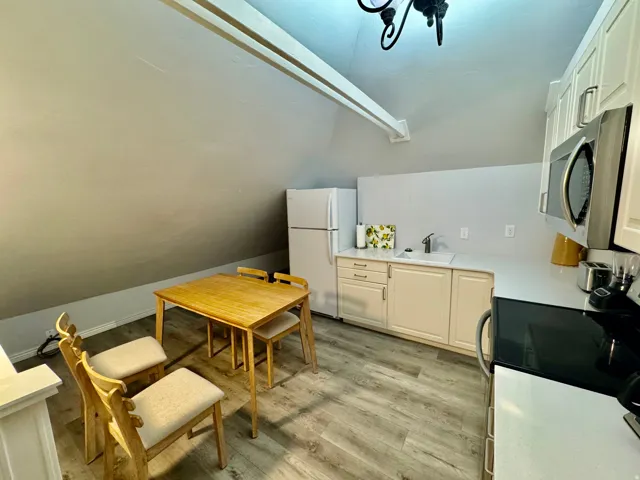Kitchenette featuring wood-finish flooring, white cabinetry, a built-in microwave, and a white refrigerator