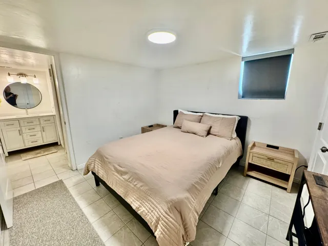 Bedroom featuring tiled flooring, a flush-mount ceiling light, and a window with a roller shade