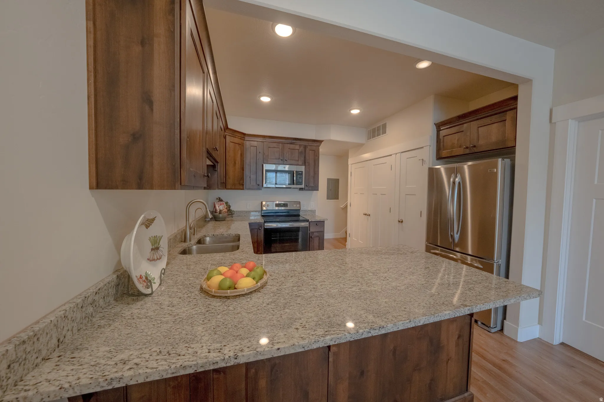 Kitchen featuring wood cabinetry, stainless steel appliances, a double basin sink, recessed lighting, and a light-toned countertop