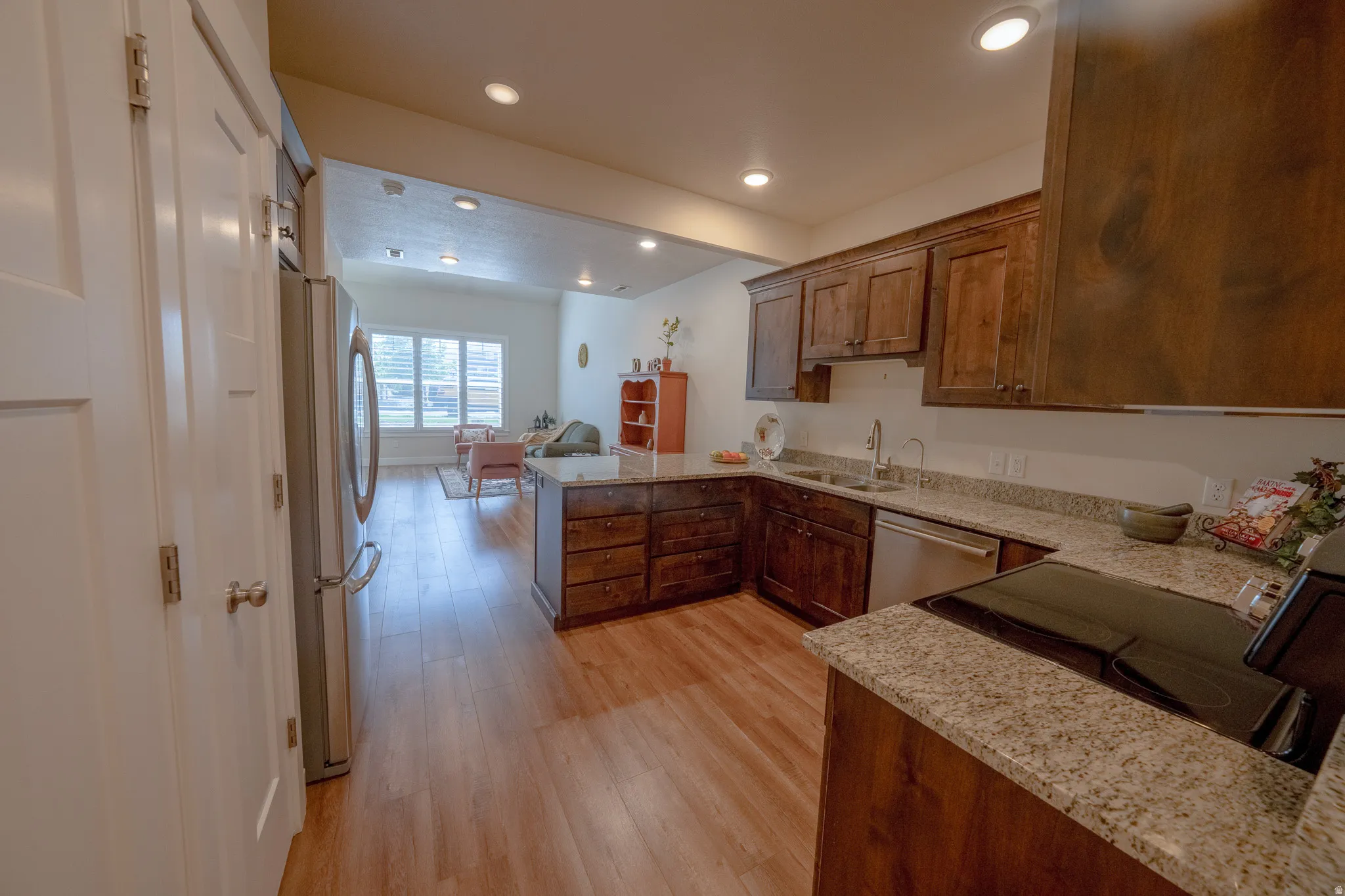 Kitchen with wood-finish flooring, dark wood cabinetry, light-toned countertops, and stainless steel appliances
