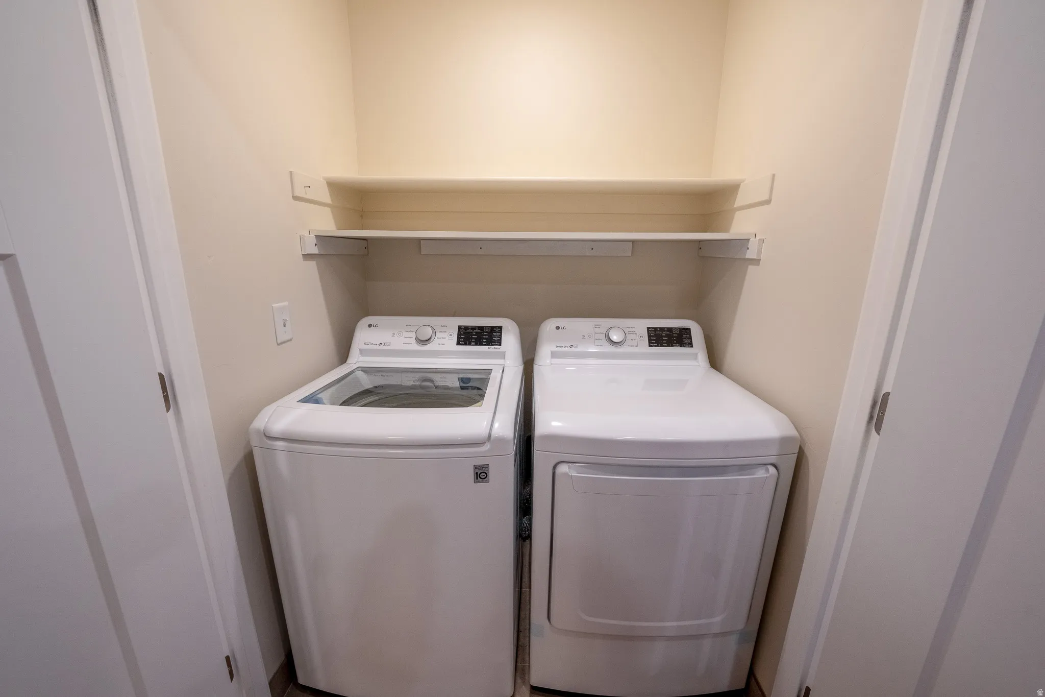 Laundry closet with built-in shelving, featuring a white washing machine and dryer