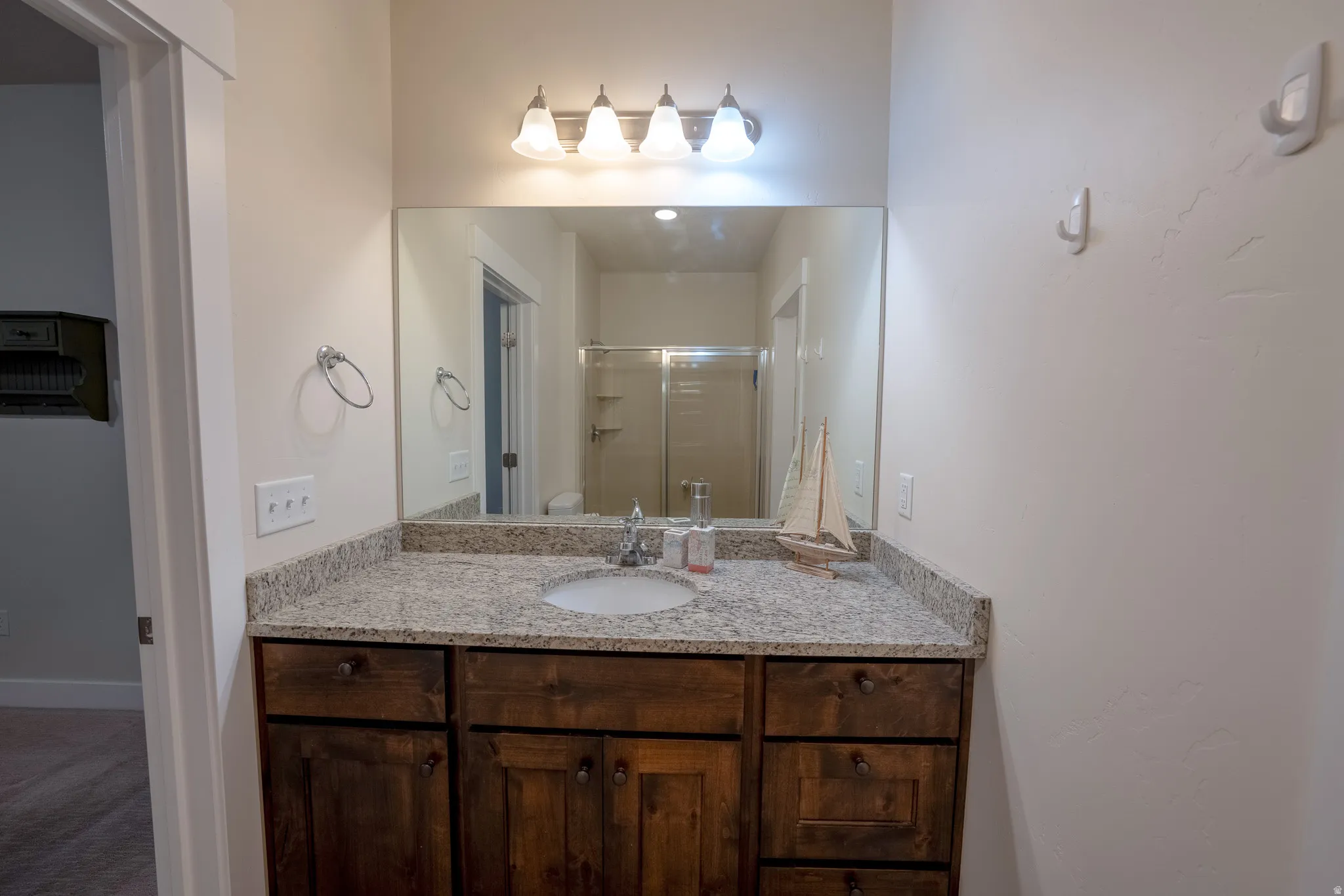 Vanity with a granite countertop, undermount sink, and dark wood-finish cabinetry