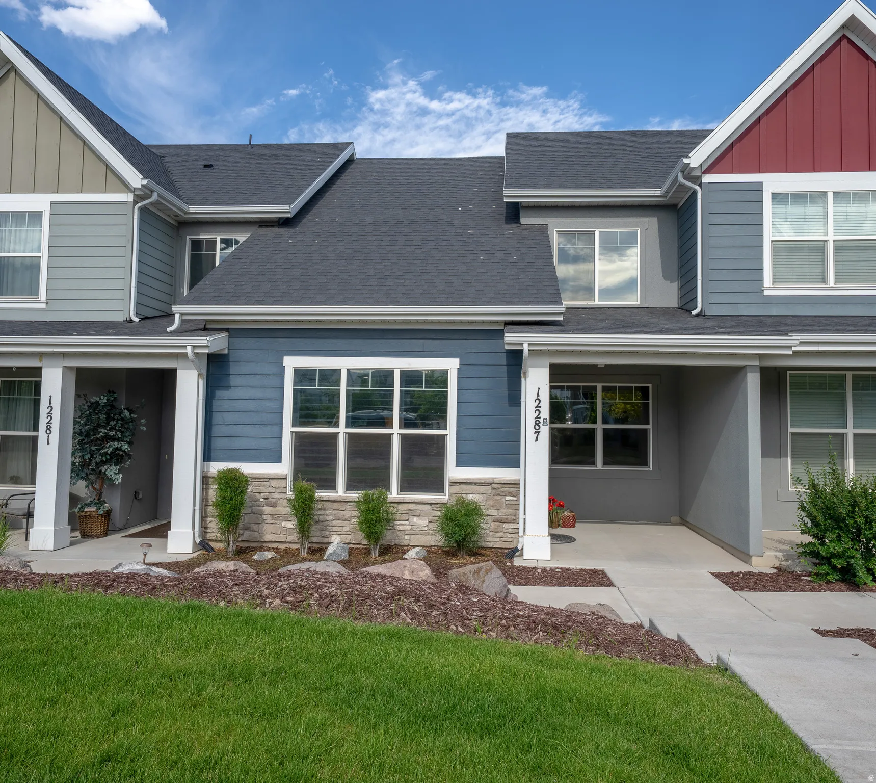 Exterior facade featuring multi-tone siding, stone accents, multiple windows, and a covered entry
