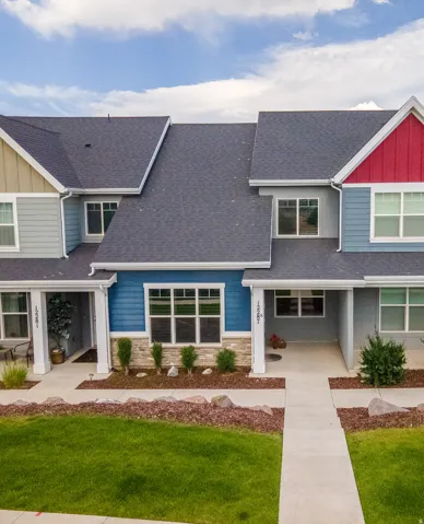 Modern townhome exterior featuring multi-toned siding, stone accents, and a covered entry