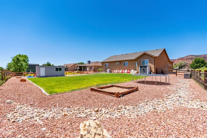 Expansive backyard with a manicured lawn, gravel landscaping, and a wooden perimeter fence