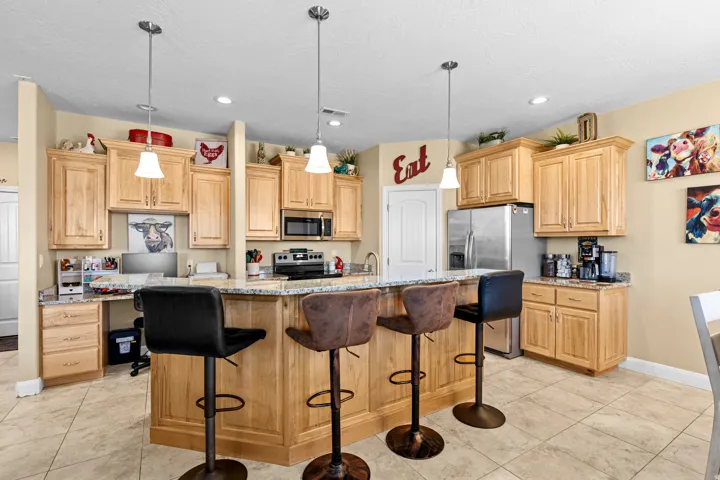 Kitchen featuring tile flooring, wood cabinetry, granite countertops, and stainless steel appliances