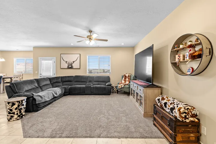 Recessed lighting, ceiling fan, multiple windows with horizontal blinds, tiled flooring, and a large area rug
