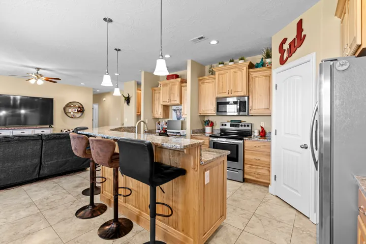 Kitchen featuring a wood-finish island with granite countertops, stainless steel appliances, and pendant lighting