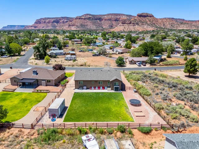 Expansive property with two detached structures, a large fenced backyard featuring a manicured lawn, and a prominent mountain backdrop