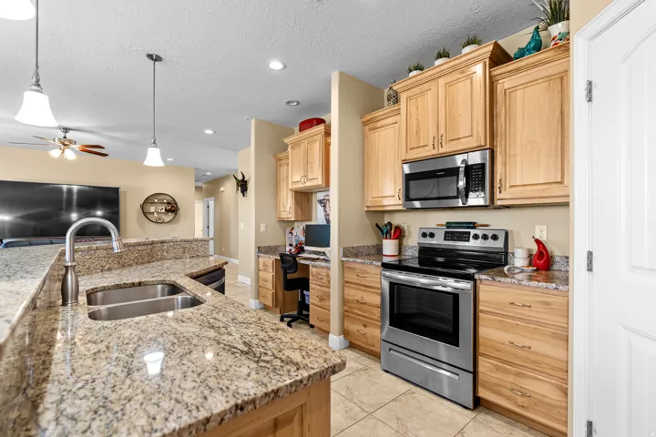 Granite countertops, stainless steel appliances, wood cabinetry, built-in desk, and tile flooring