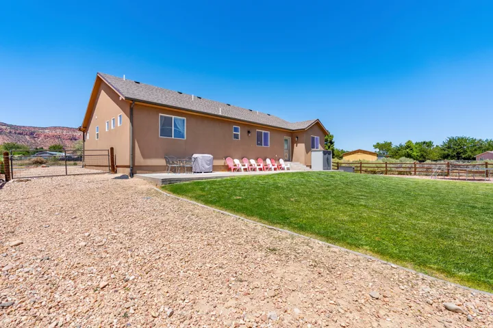 Stucco exterior with multiple windows, leading to a concrete patio