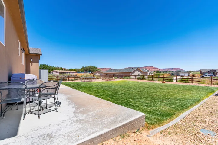 Concrete patio with stucco exterior, expansive lawn, and distant rock formations