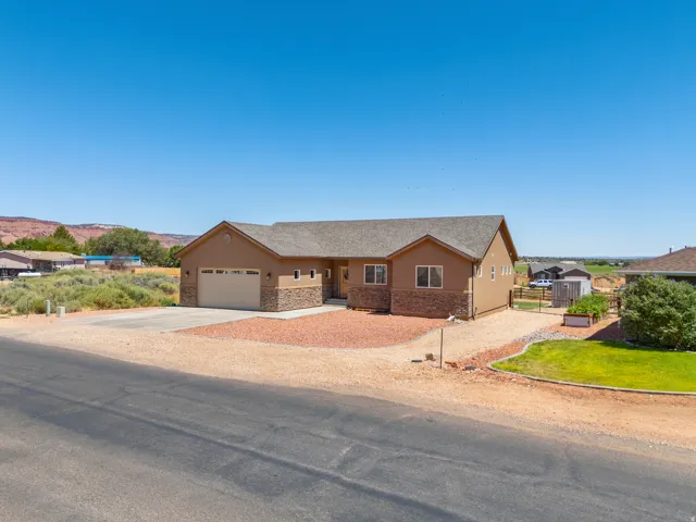 Single-story residence featuring a two-car garage, stone and stucco exterior, and a gravel driveway