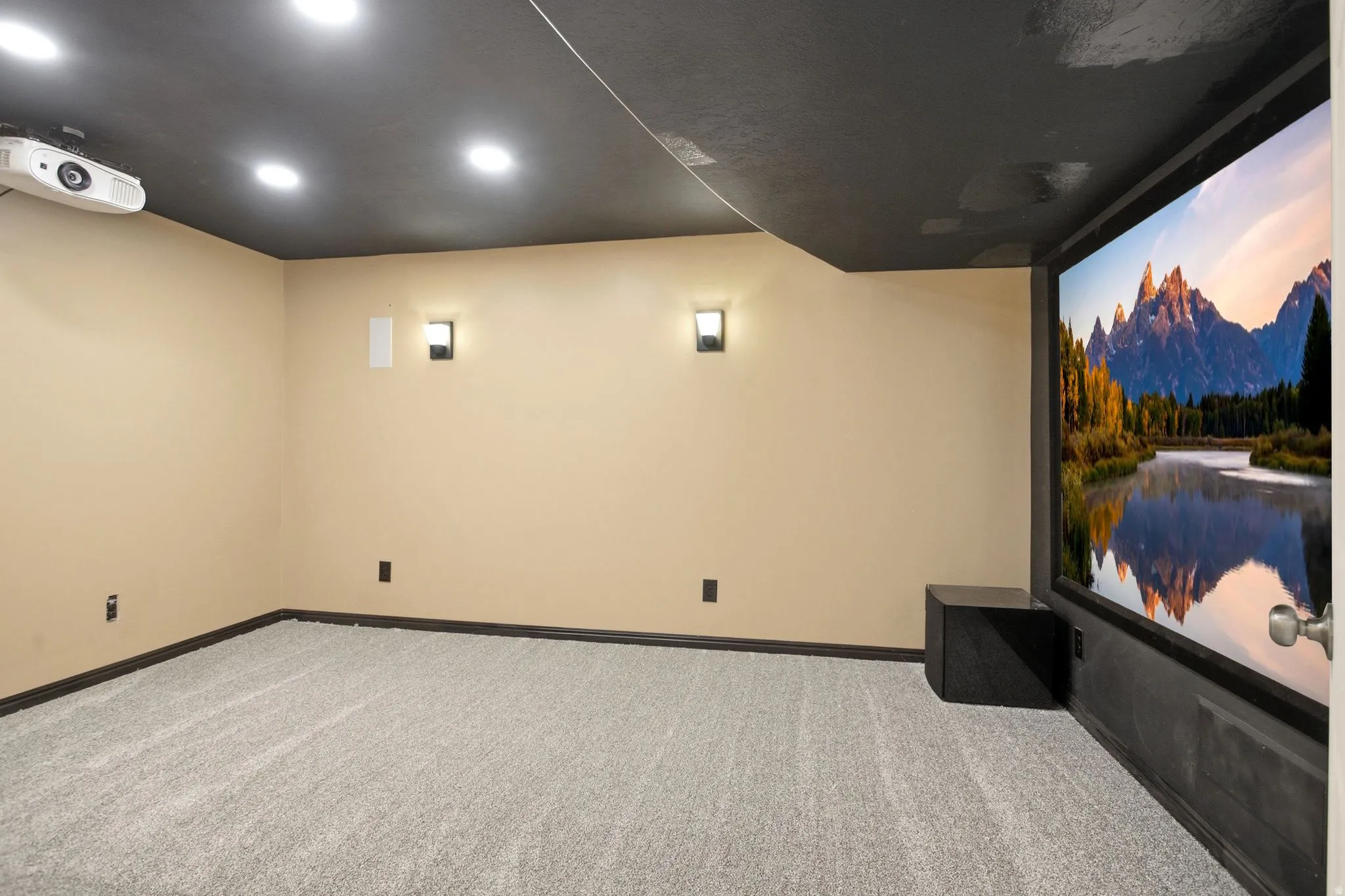 Home theater space featuring a large projection screen, wall-mounted projector, recessed lighting, and wall sconces