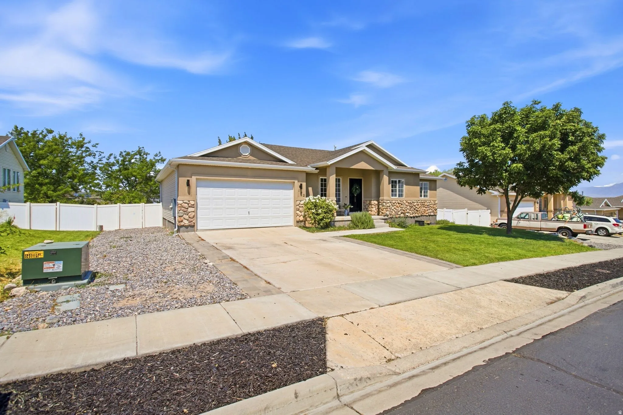 Light-toned stucco exterior with stone accents and a white garage door