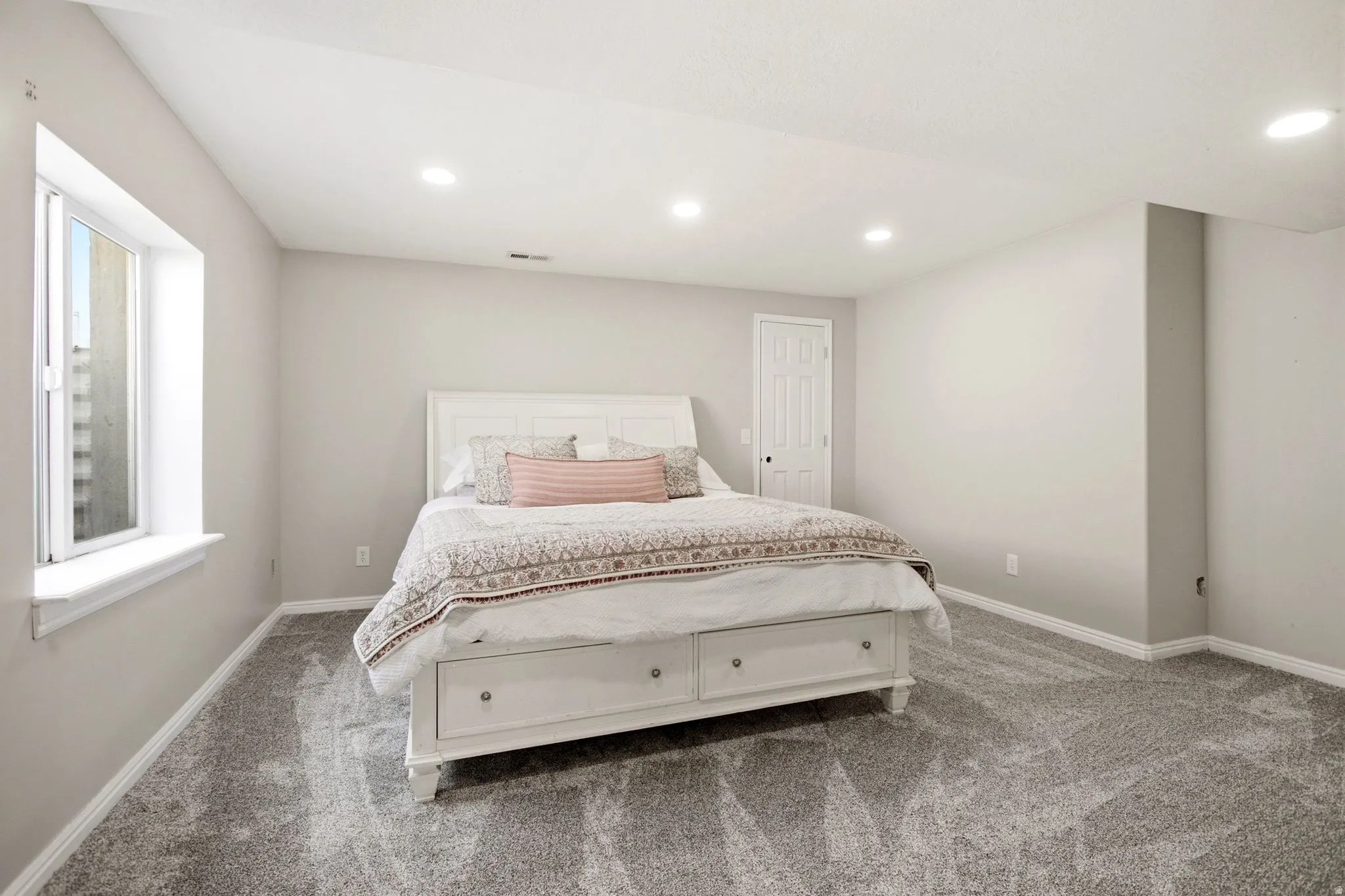 Recessed lighting, gray carpeting, neutral wall finishes, and a white interior door