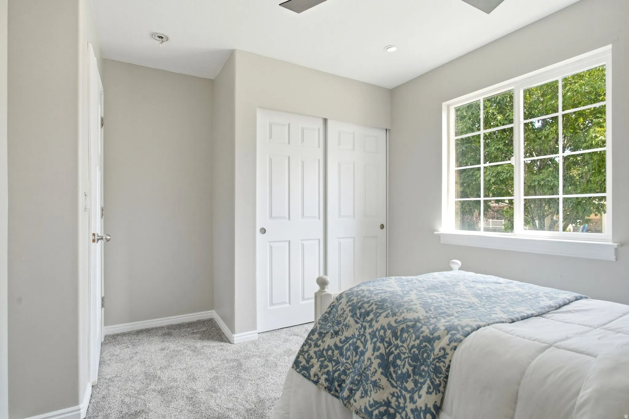 Carpeted flooring, recessed lighting, and a large window with white grid panes