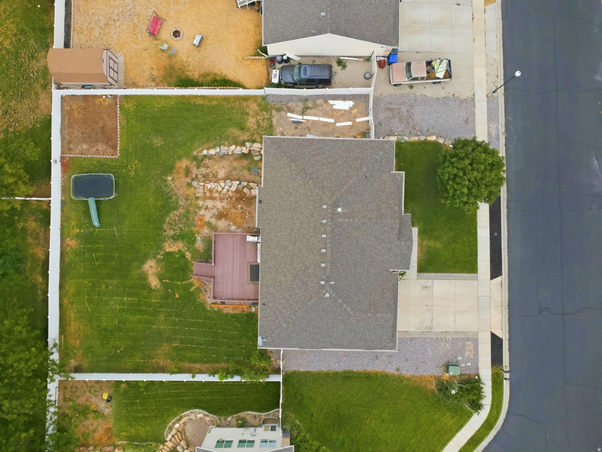 Expansive lot featuring a large lawn area, wood-finish deck, paved driveway, and detached storage shed