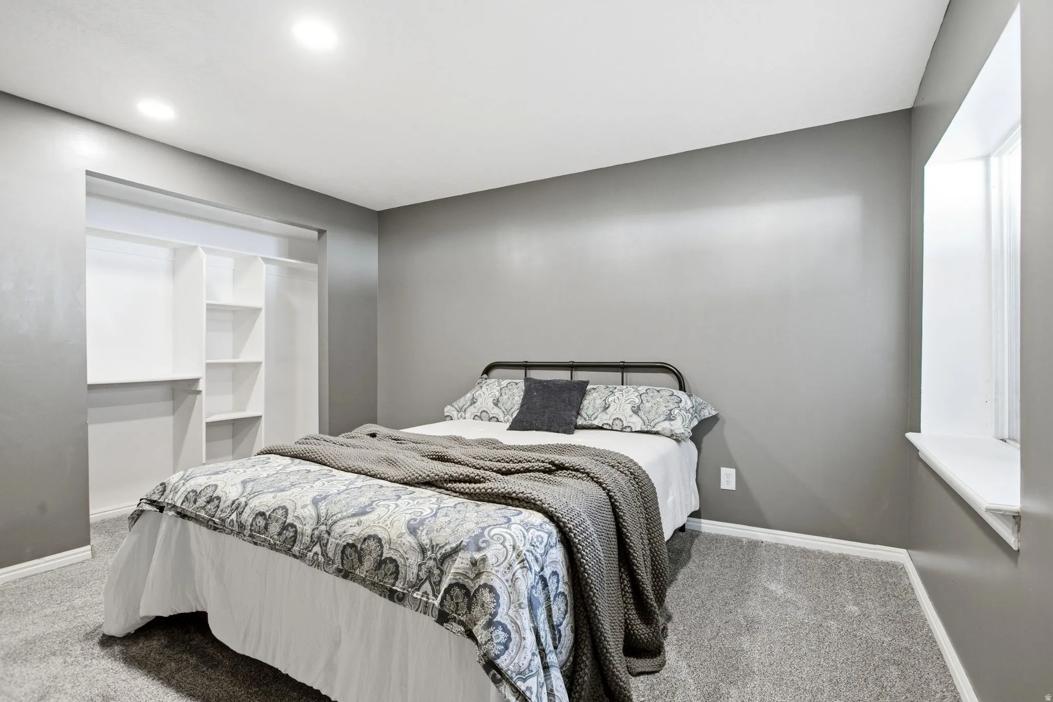 Recessed ceiling lighting illuminates the room with gray walls and complementary gray carpeting