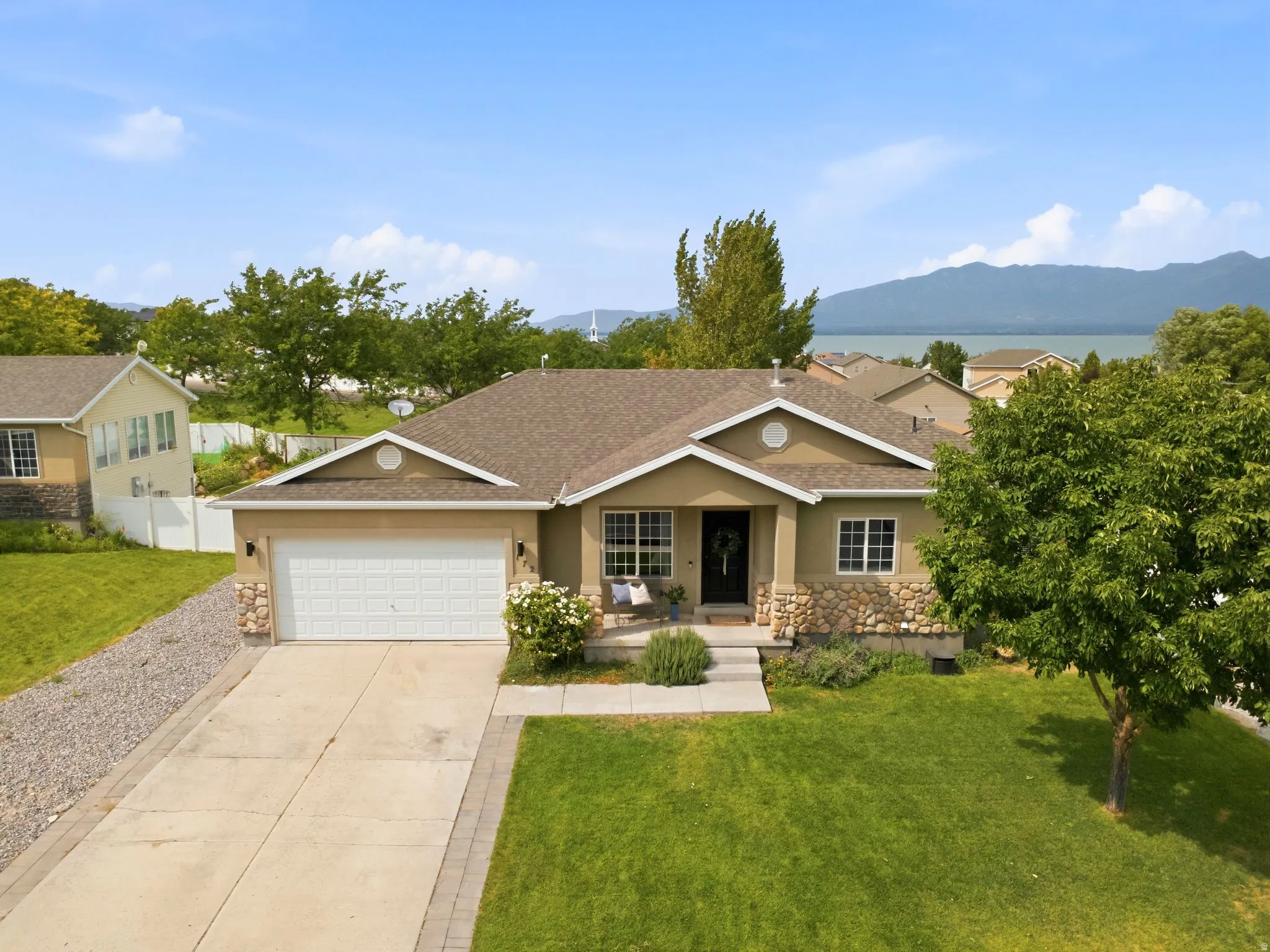 Single-story residence featuring a two-car garage, stone and stucco exterior, and a concrete driveway