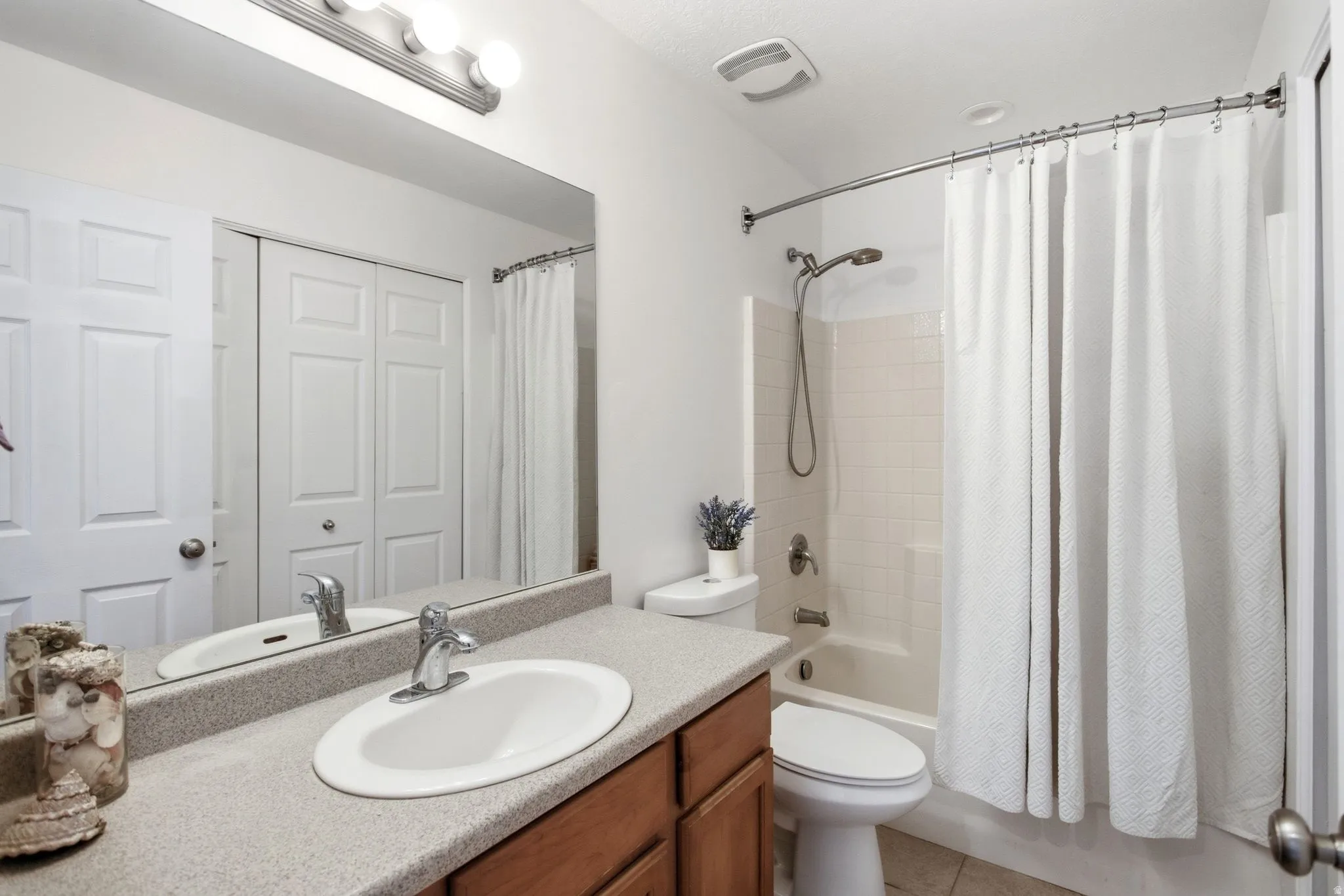 Bathroom featuring a single vanity with an integrated sink, a light-colored countertop, and wood-finish cabinetry