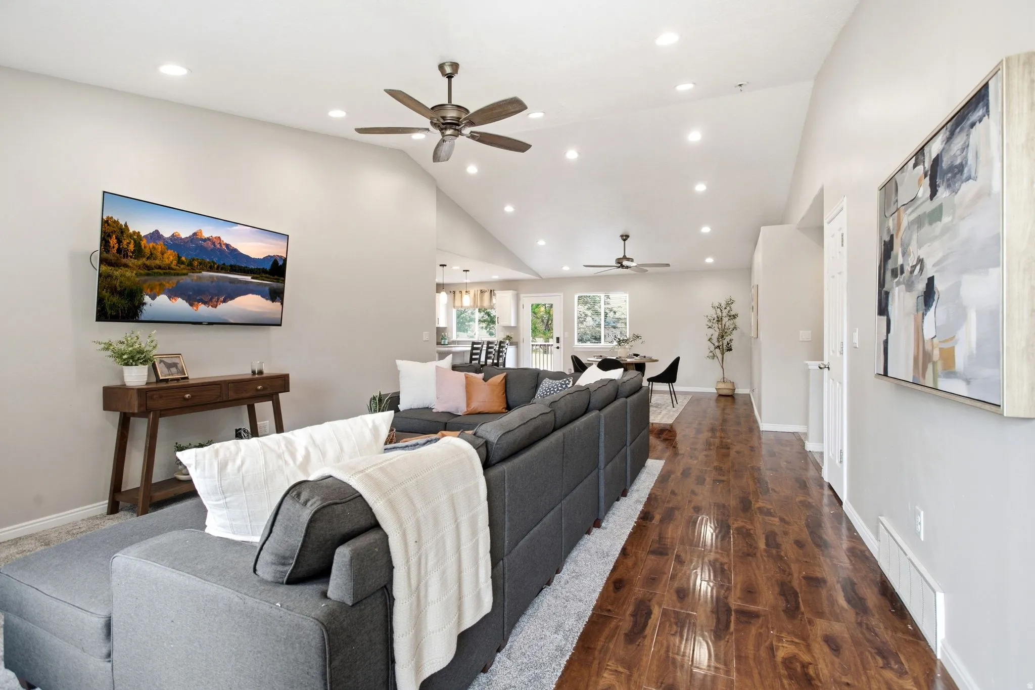 Vaulted ceilings with recessed lighting, wood-finish flooring, and ceiling fans