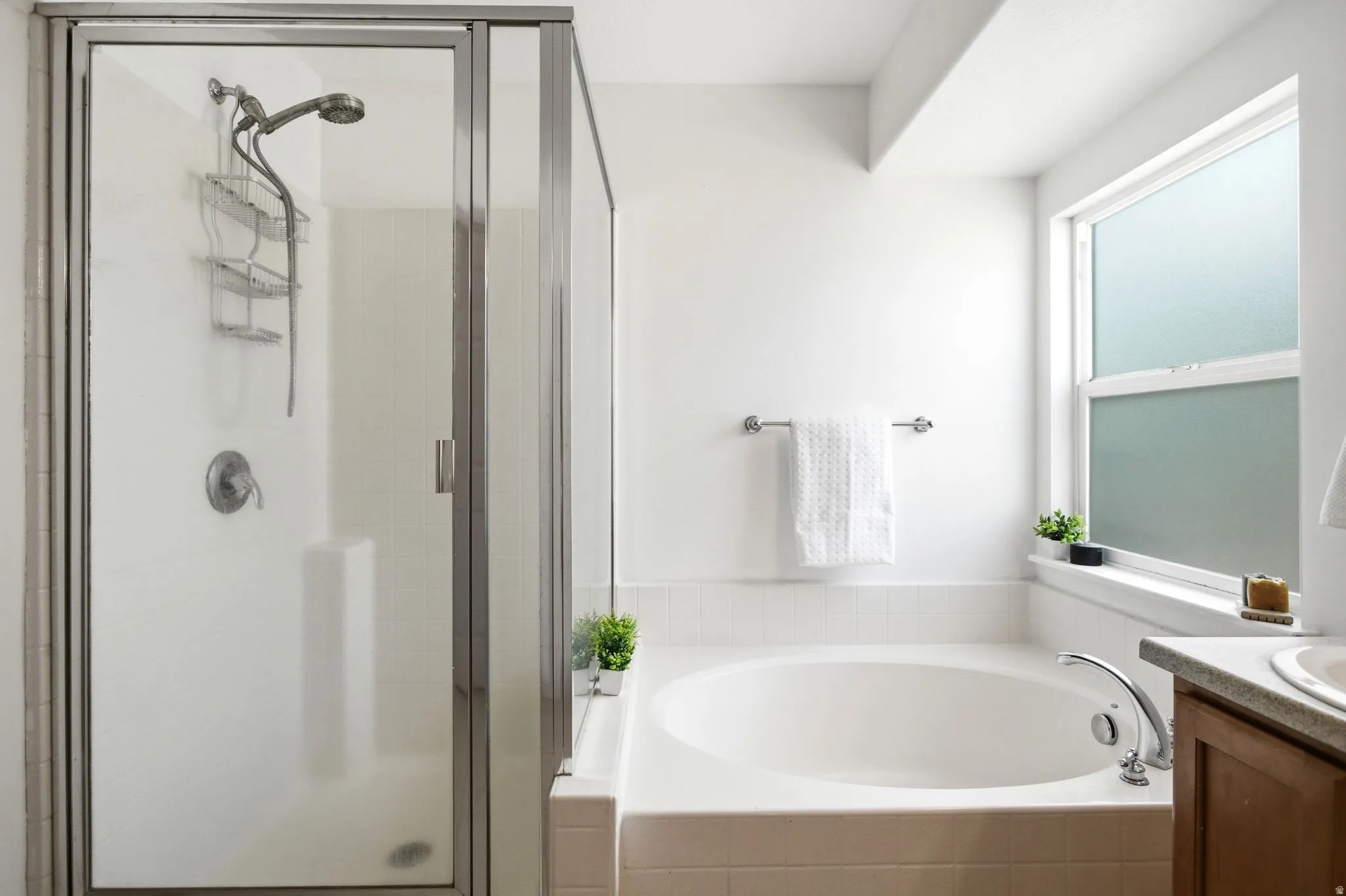 Primary suite Enclosed shower with a handheld shower head, a built-in soaking tub, a window with frosted glass, and a wood-finish vanity with an integrated sink