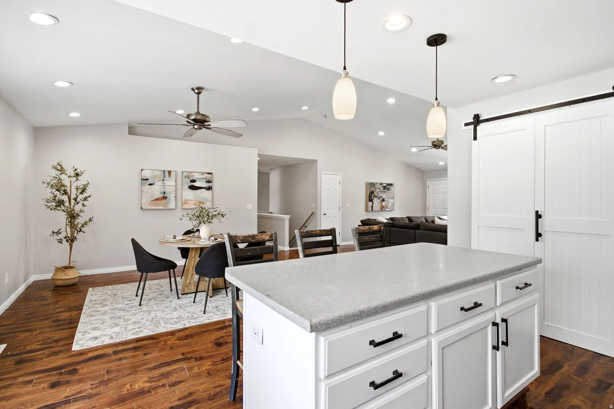 Kitchen island with a light-toned countertop, white cabinetry with dark hardware, and two pendant lights