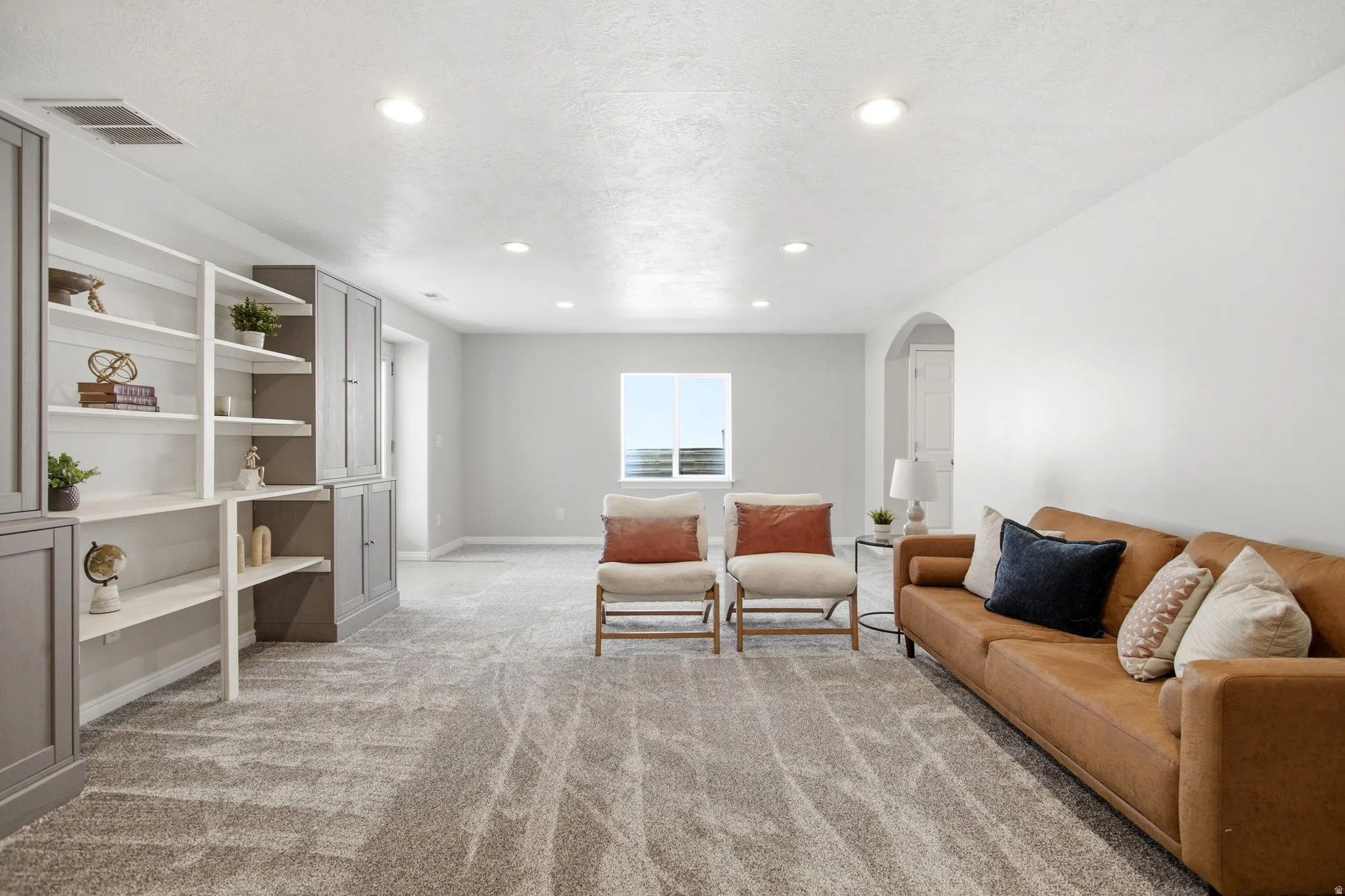Recessed lighting, light gray painted walls, and built-in shelving with cabinetry