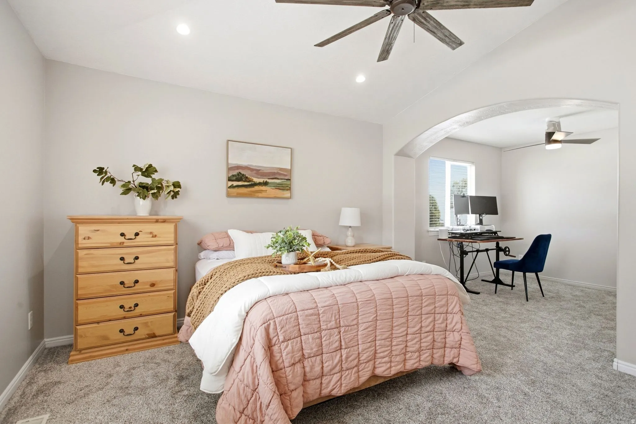 Primary suite with arched doorway feature, recessed lighting, ceiling fans, window with blinds, and carpeted flooring