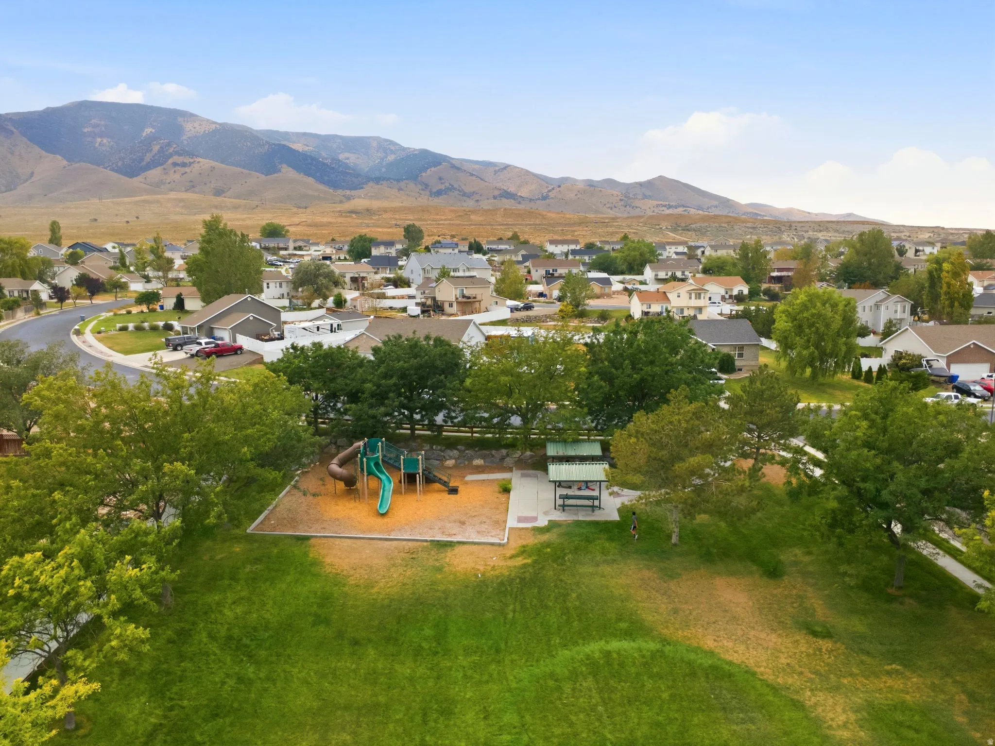 Community green space featuring a playground, shaded picnic area, and mountain backdrop
