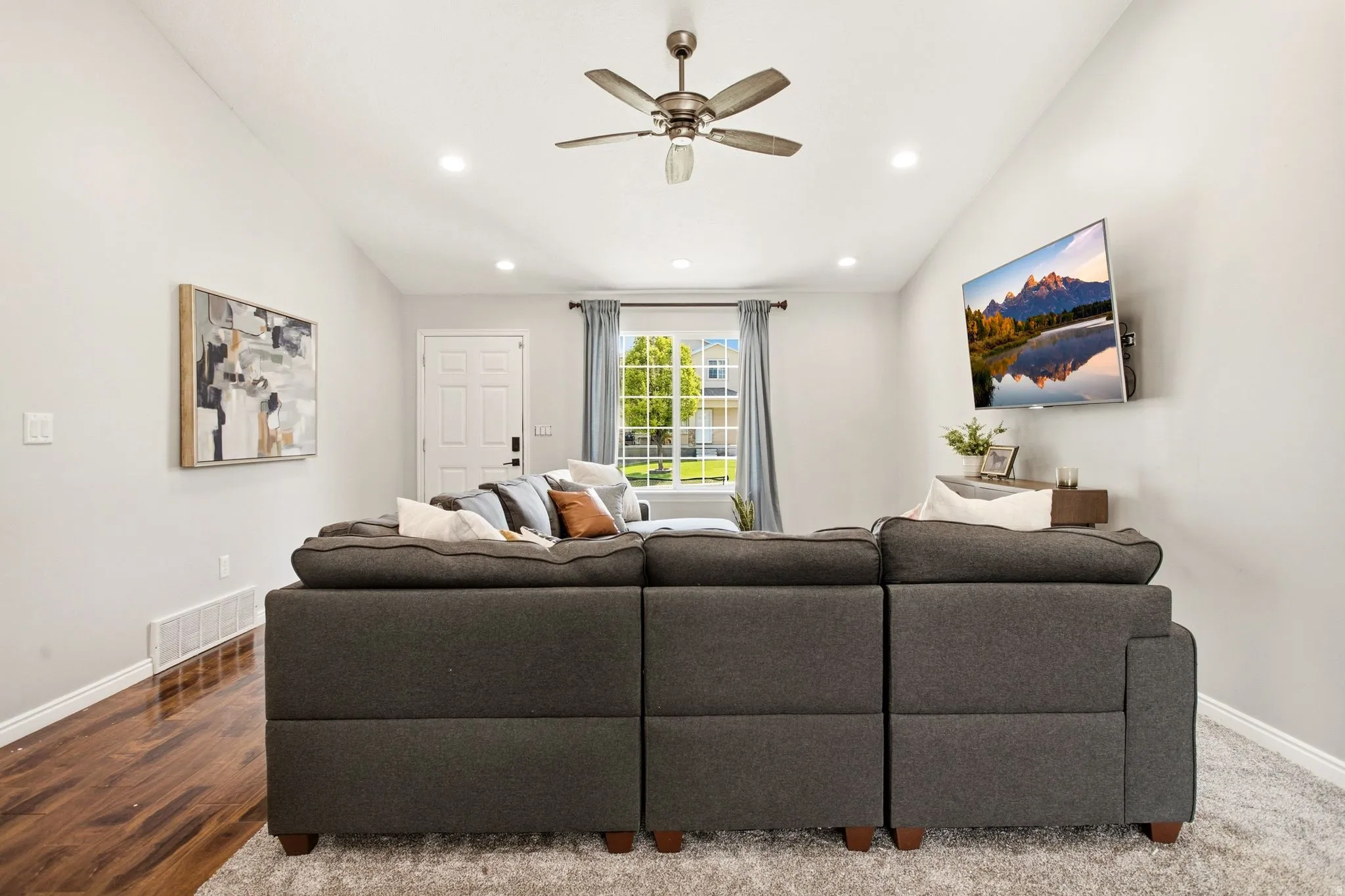 Sloped ceiling with recessed lighting, wood-finish flooring, ceiling fan, and white paneled door