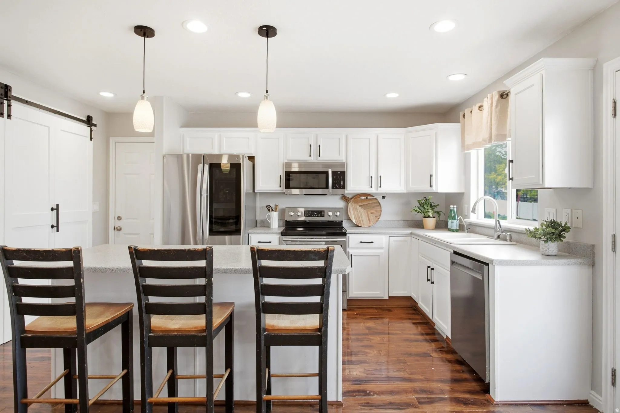 Kitchen featuring wood-finish flooring, white cabinetry, stainless steel appliances, a kitchen island, and recessed lighting