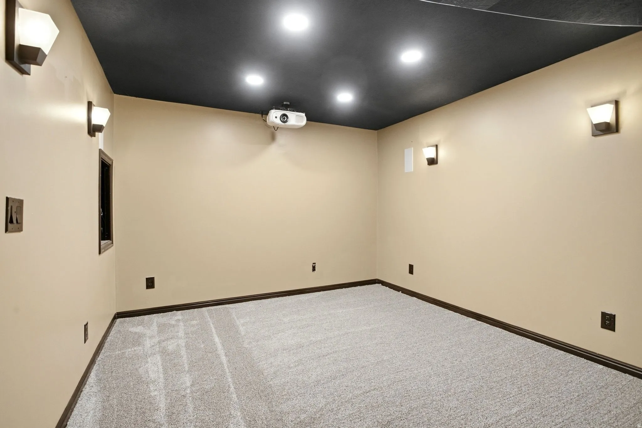 Recessed ceiling lighting, wall-mounted sconce lighting, dark ceiling finish, light-colored walls, and gray carpet flooring
