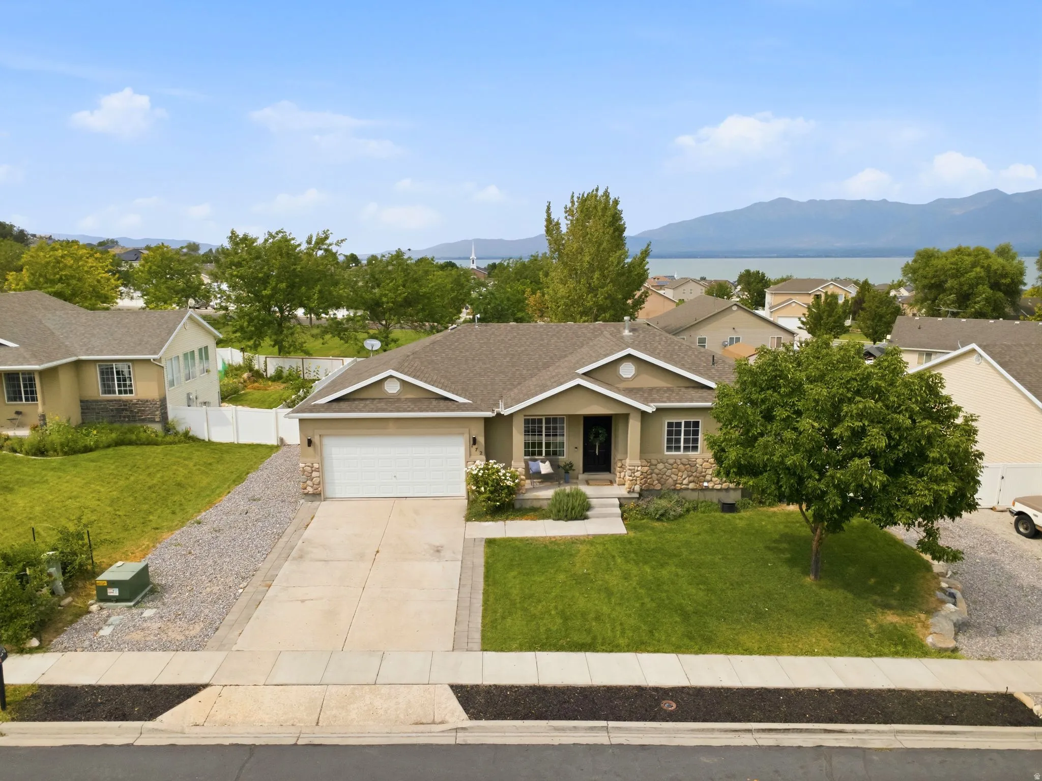Exterior featuring a light tan facade with stone accents, a two-car garage, and a concrete driveway