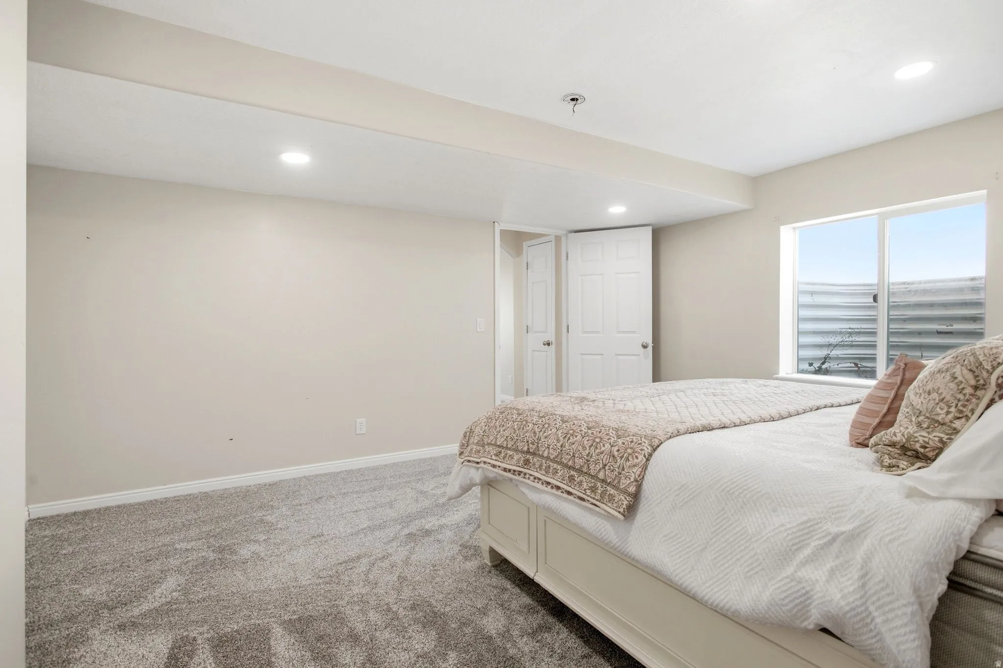Carpeted room with recessed lighting and a window