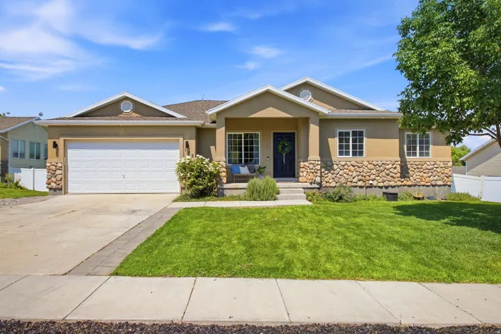Stucco exterior with stone accenting, an attached two-car garage, a concrete driveway, and a covered entry