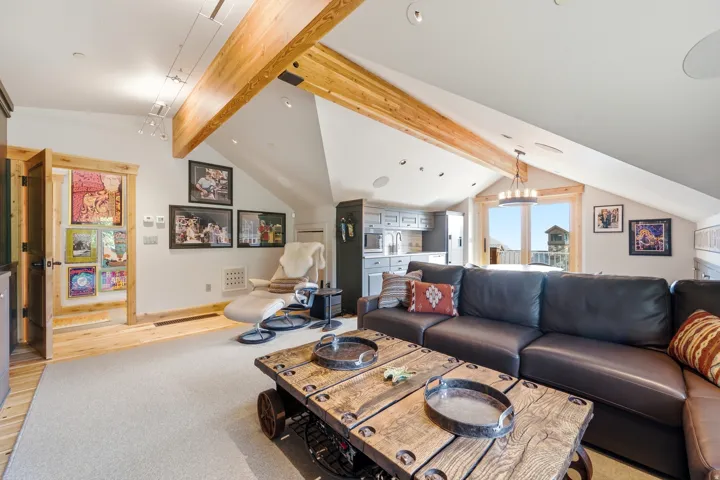 Vaulted ceilings with exposed wood beams, recessed lighting, and a built-in wet bar