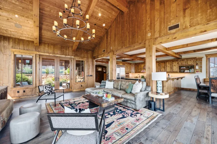 Vaulted wood-paneled ceiling with exposed beams, wood-finish flooring, and a large chandelier