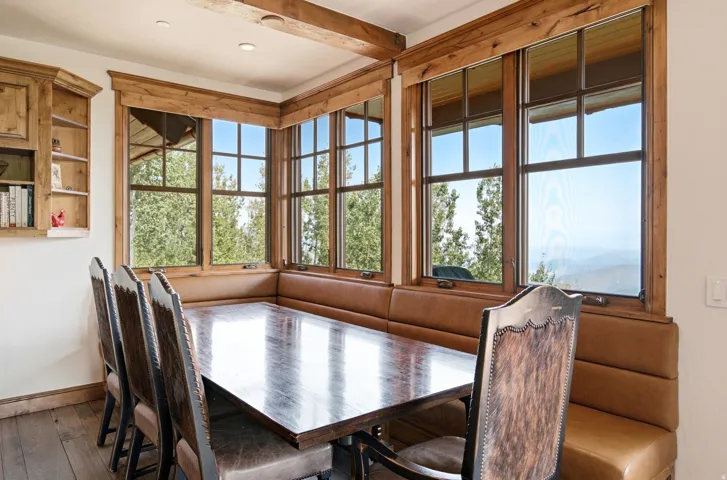 Built-in corner banquette seating with upholstered cushions, wood-finish window frames, and wood-finish ceiling beams