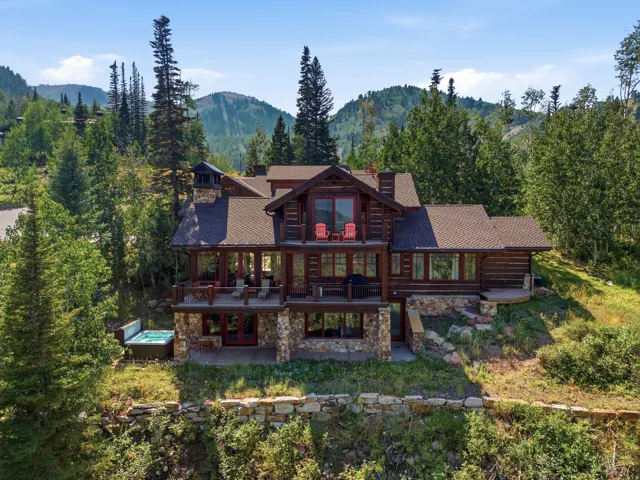 Wood-sided residence featuring multiple outdoor decks, a stone-clad foundation, and an outdoor spa