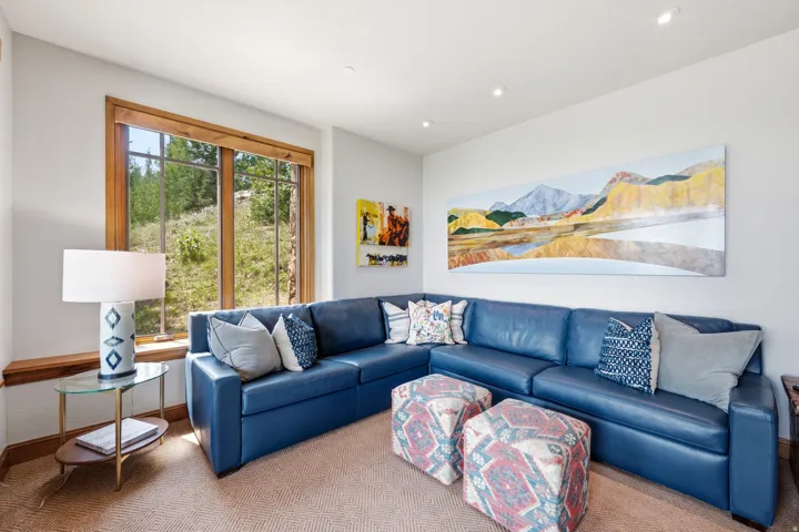Recessed lighting, wood-trimmed picture windows, and neutral wall tones complement the textured carpeting