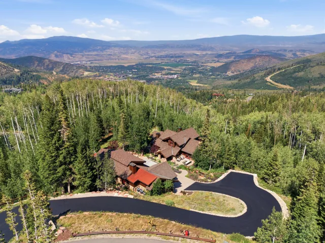 Extensive mountain property with a winding paved driveway and a multi-level residence, surrounded by mature trees