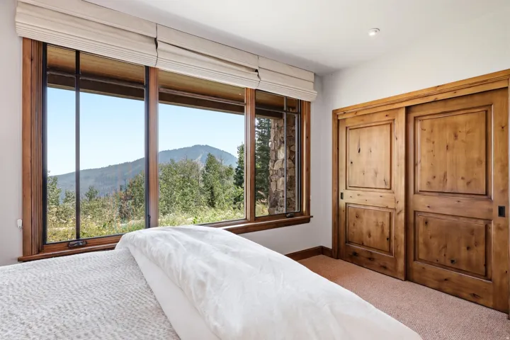Expansive window offering mountain scenery, wood-framed windows, wood-finish sliding doors, and neutral wall color