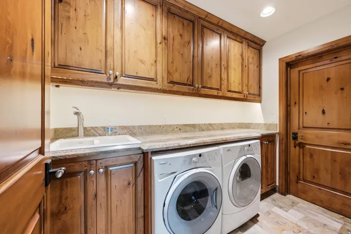Custom wood cabinetry, stone countertop, integrated sink with gooseneck faucet, tile flooring, and recessed lighting